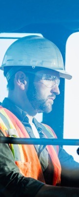 Male construction worker in safety vest and hardhat operating equipment at construction site