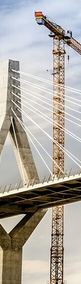 White bridge under construction with red crane behind