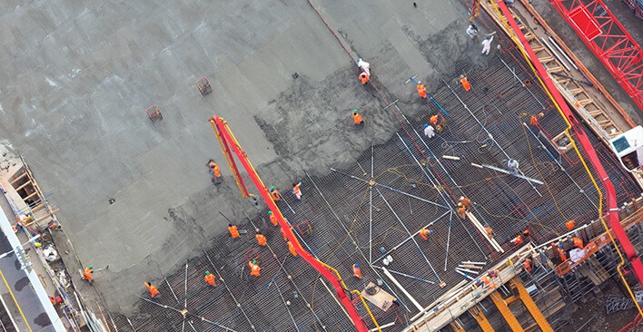 Aerial view of workers surrounded by equipment laying concrete at construction site