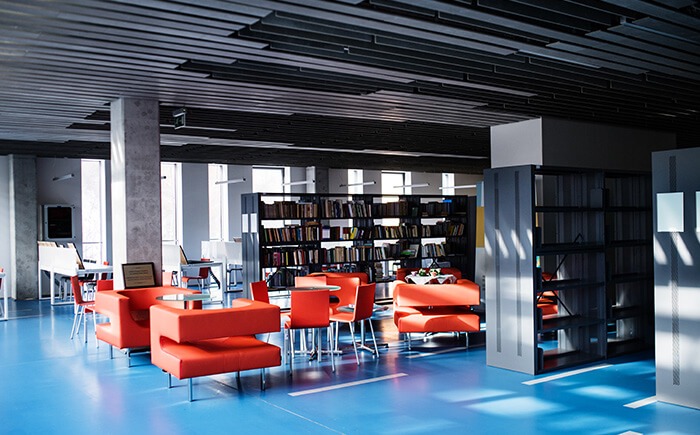 School library shelves, surrounded by modern orange furniture