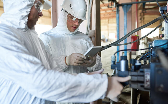 Two workers dressed in protective gear providing nuclear plant decontamination and decommissioning consulting