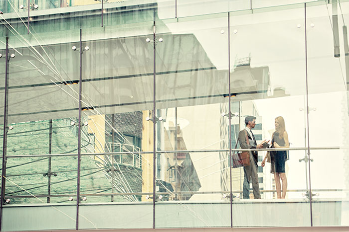 Real estate development consultants conversing on building walkway. 