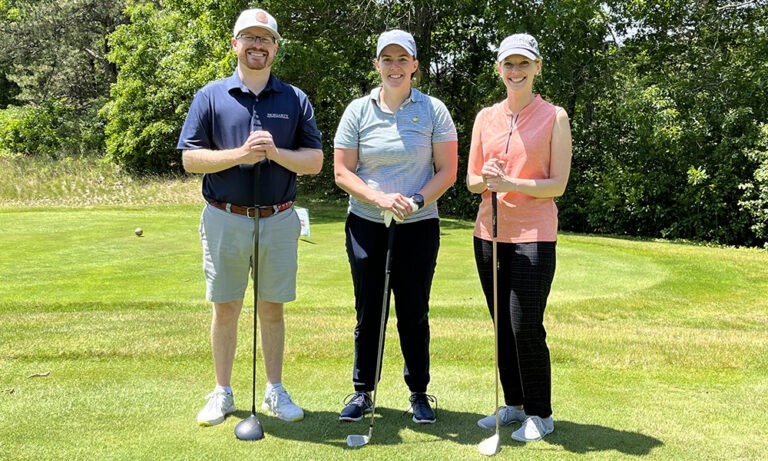 Three golf players from John Moriaty and Associates standing on the green during the 13 Annual Charity Golf Tournament.