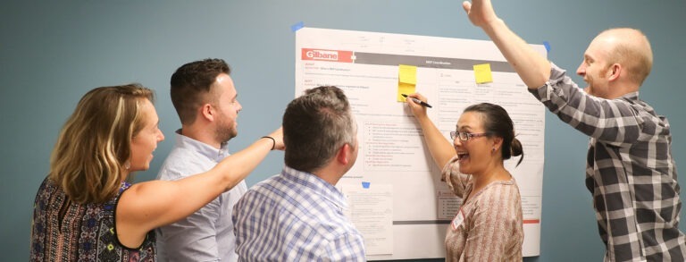 Staff surround Gilbane poster, smiling.