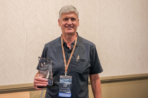 Dan Peluso holding the 2023-2024 Public, Small-Budget Outstanding Project Award.